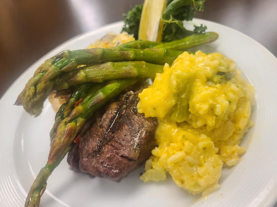 Plate of steak, asparagus, and cheesy rice with garnish