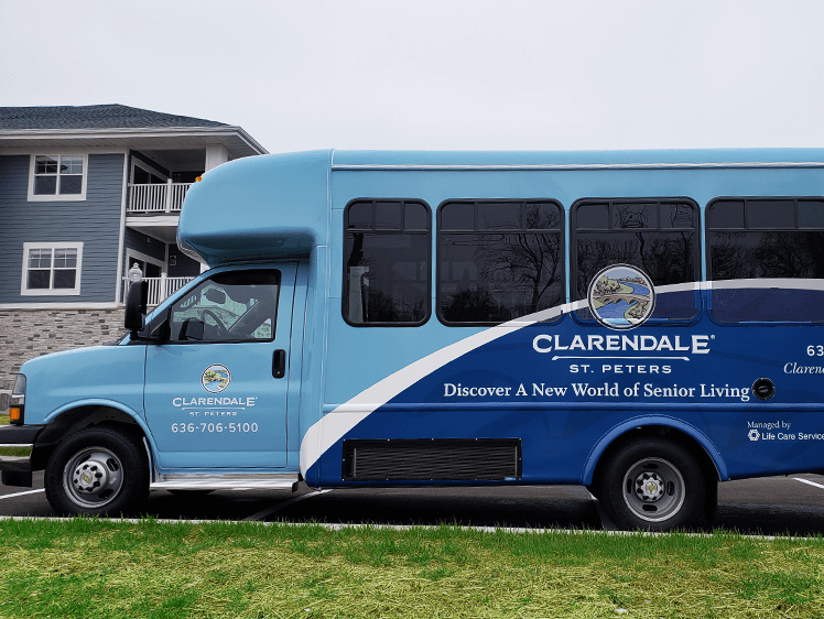 Clarendale St. Peters bus displaying senior living advertising in front of a residential building.