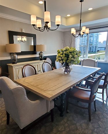 Elegant private dining room with a large wooden table, cushioned chairs, and chandelier lighting.