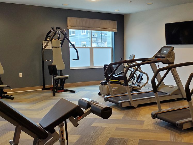 Modern gym with various exercise equipment including treadmills, a weight machine, and a stationary bike