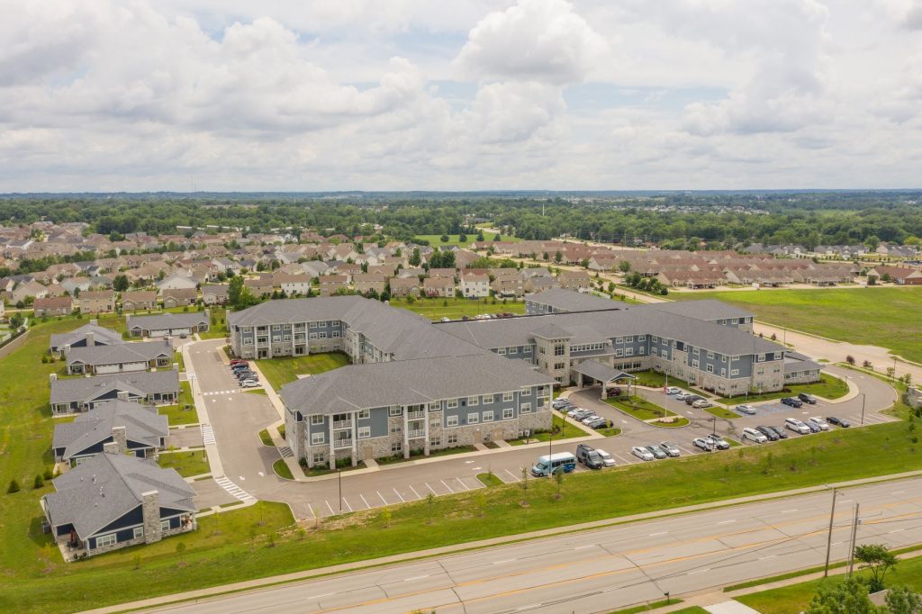 Aerial view of a large residential community with houses and a main building surrounded by greenery.