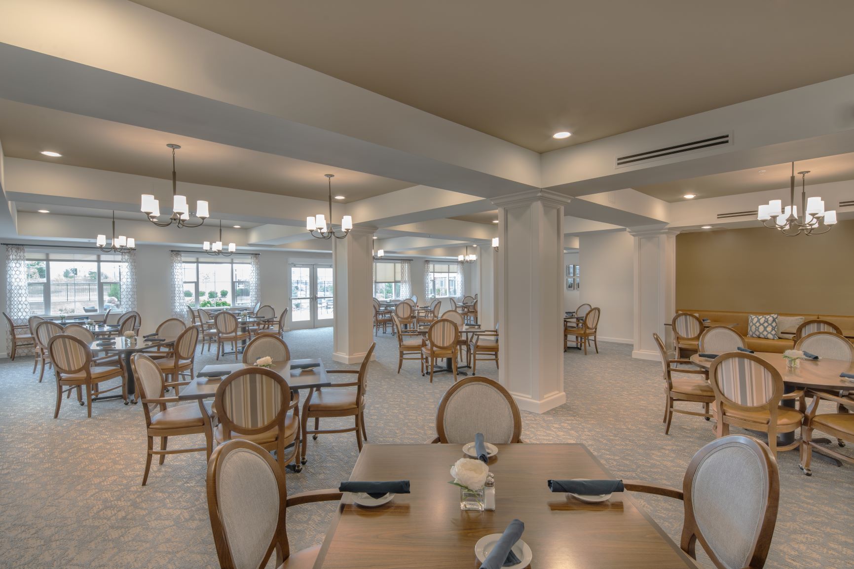 Elegant Dining Area with Chandeliers Spacious dining area with elegant chandeliers, wooden tables, and upholstered chairs.