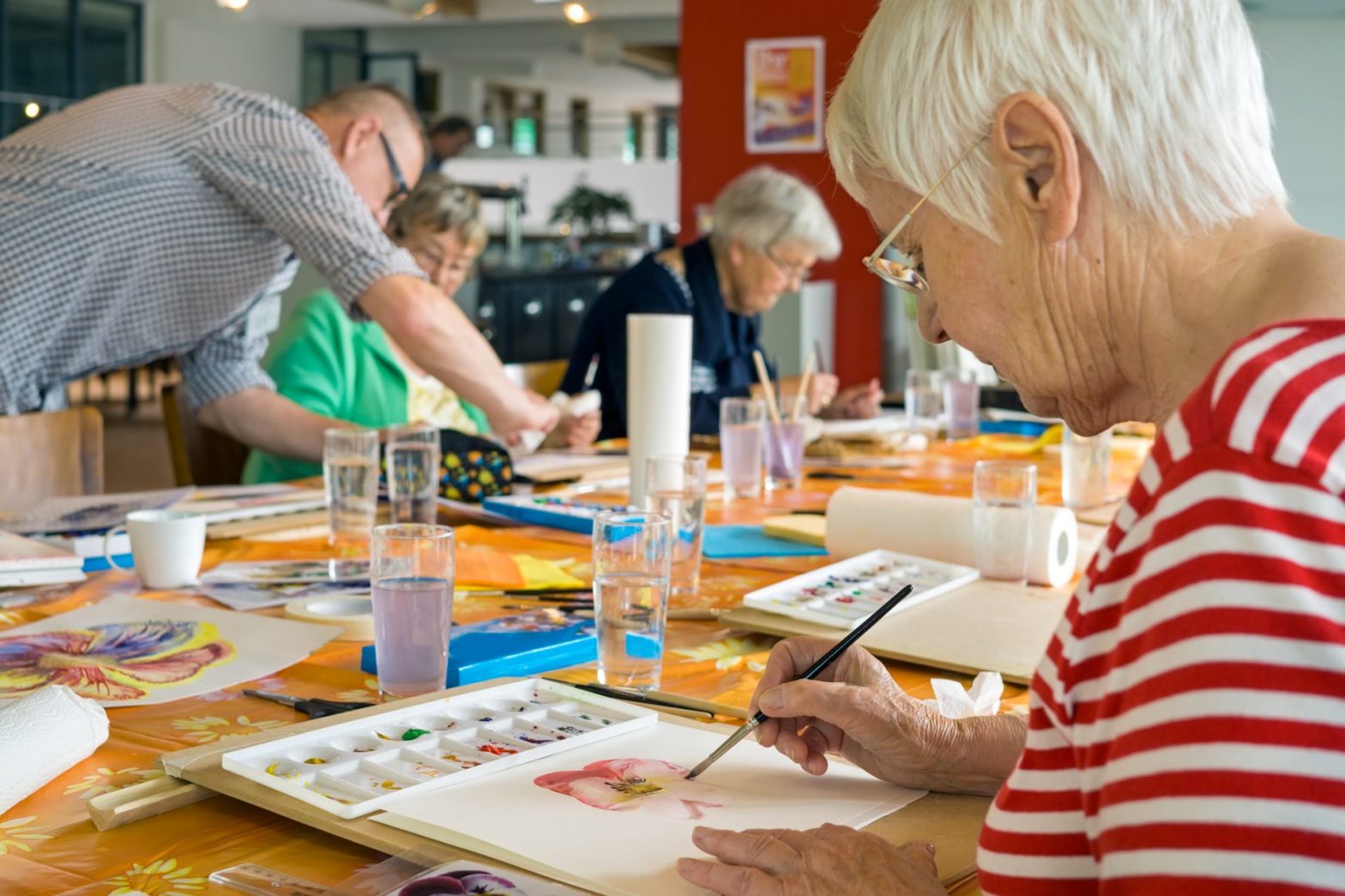 Senior adults engaged in a painting class, focusing on watercolor techniques and social interaction.