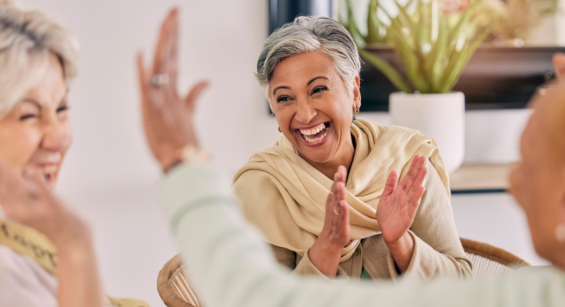 Senior woman clapping and laughing with friends