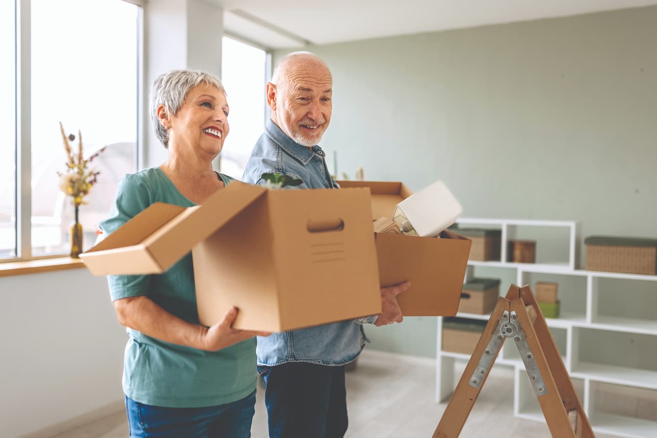 senior couple carrying moving boxes