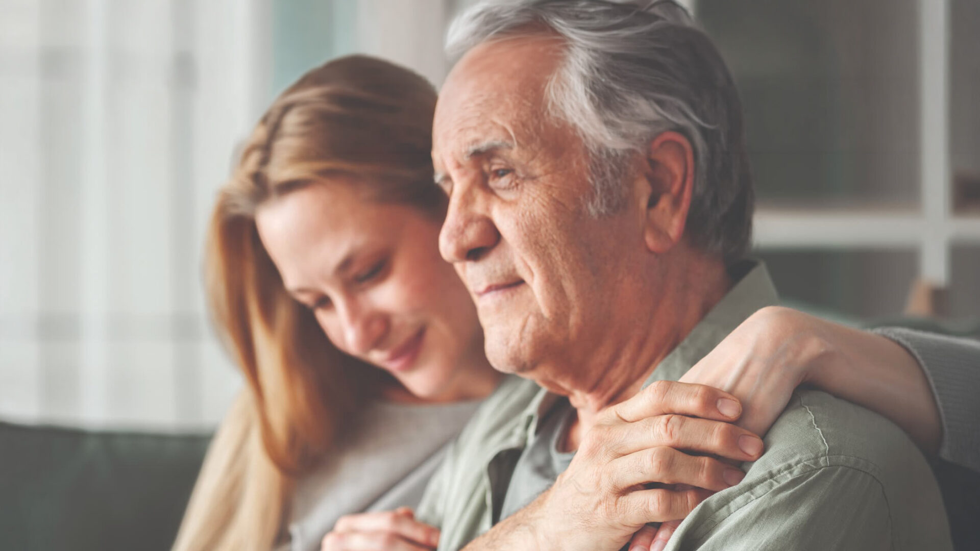 Senior man looking off into the distance as woman embraces him