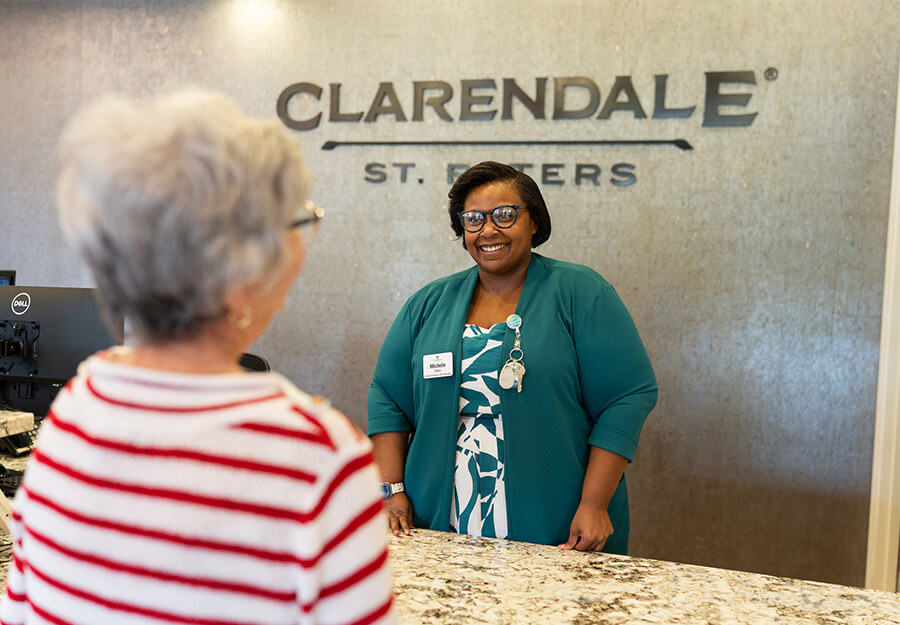 Receptionist greets a resident at the Clarendale St. Peters community reception area.