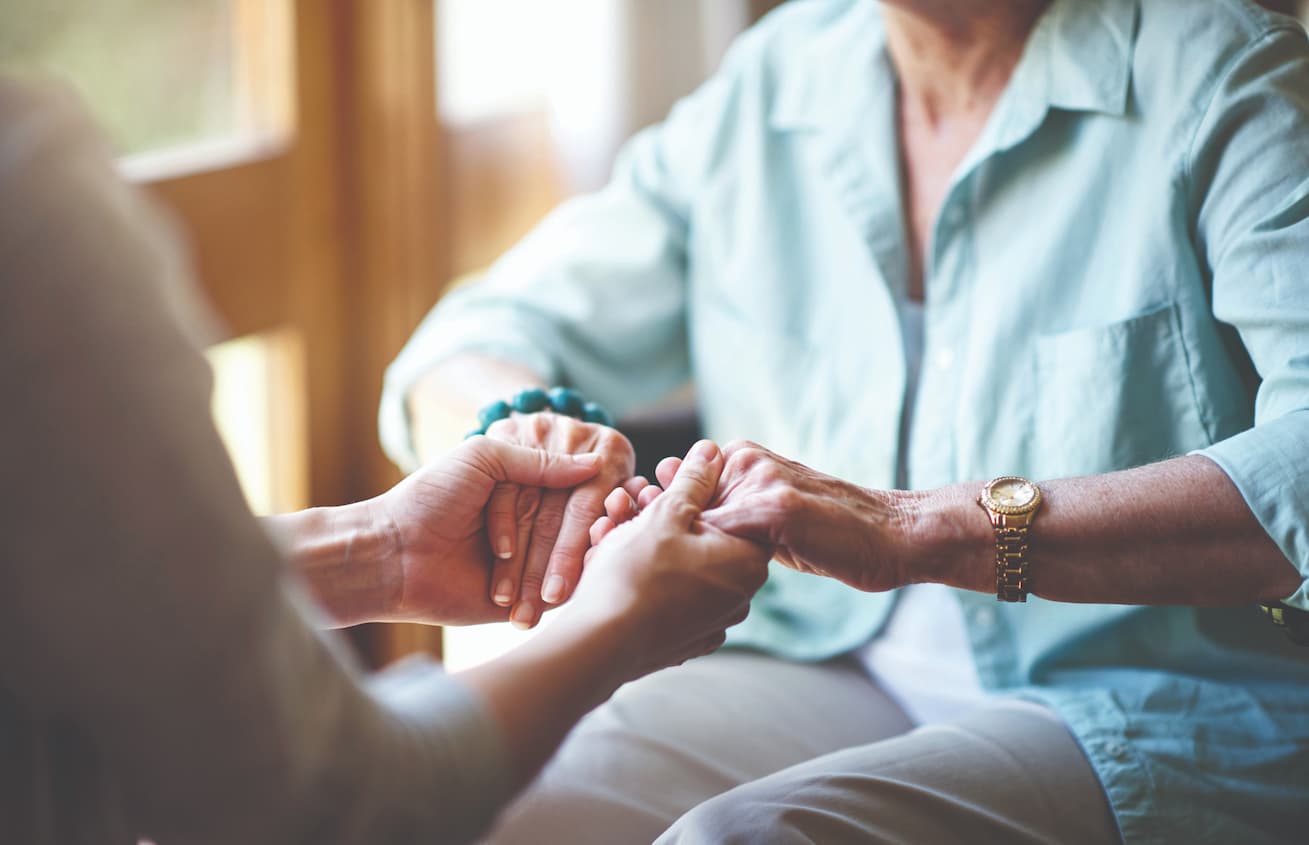close up of woman and caregiver holding hands
