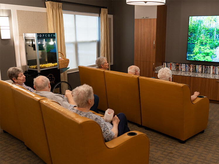 Residents enjoying a movie in a cozy communal viewing room with a popcorn machine.