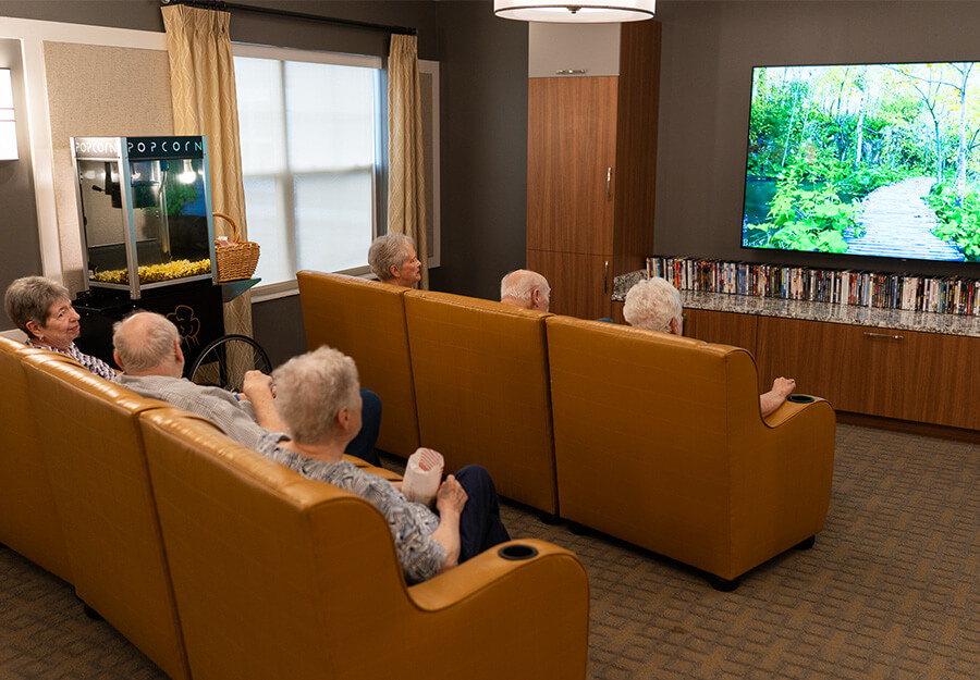Residents watching a movie in a cozy lounge area with popcorn machine and large TV