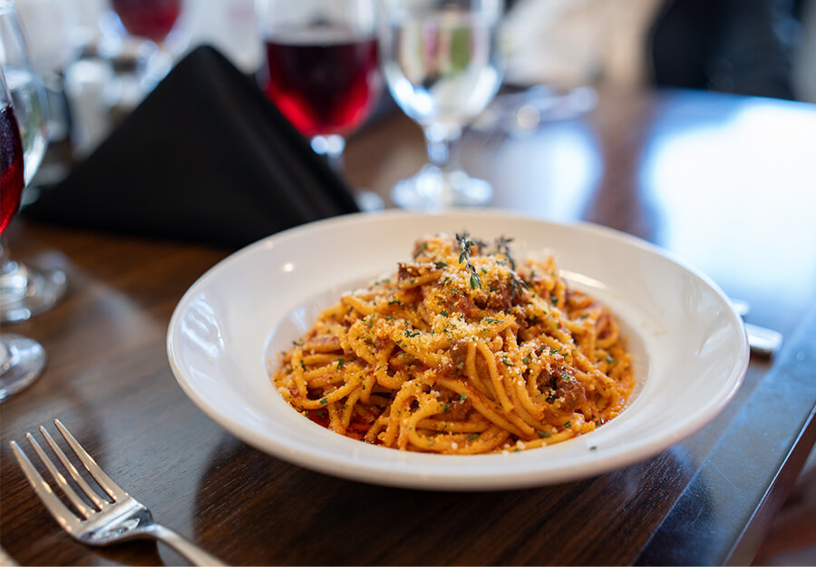 gourmet-spaghetti-bolognese-dining5 Delicious spaghetti bolognese with parmesan in a white bowl on a wooden table.