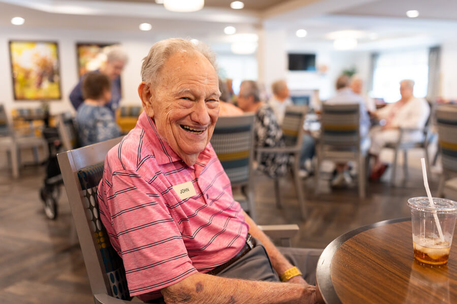 Senior smiling at a dining table.